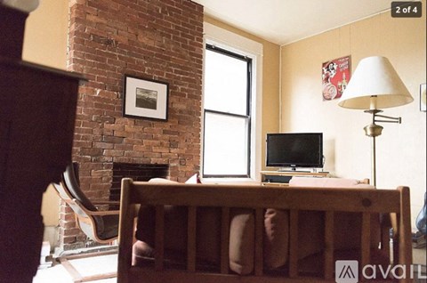 A bedroom with a brick fireplace and a television.