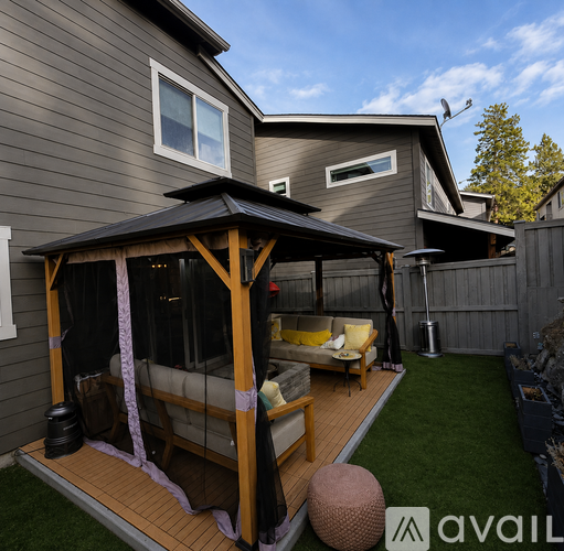 A wooden gazebo with a canopy is situated on a wooden deck.
