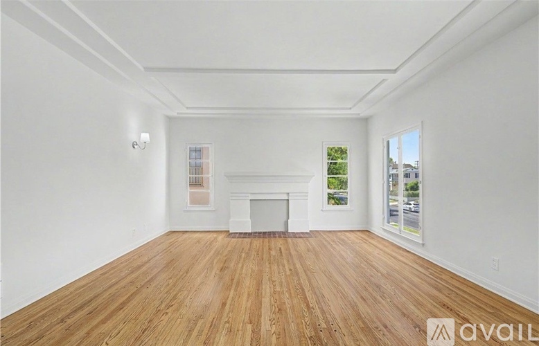 A spacious room with wooden flooring and a fireplace.