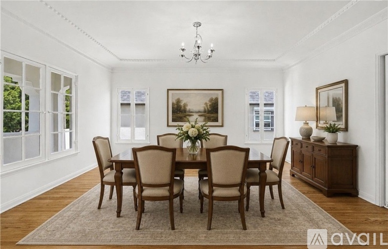 A dining room with a table set for six and a chandelier hanging from the ceiling.