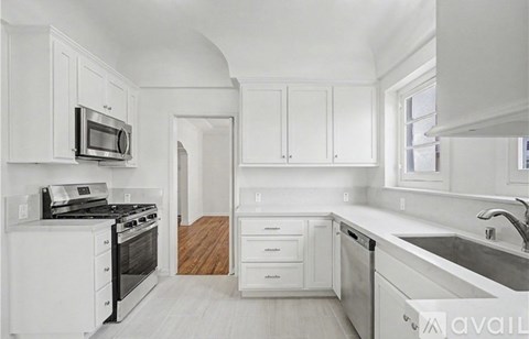 A kitchen with white cabinets and appliances.