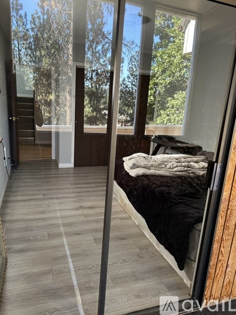 A bedroom with a bed and a window overlooking a tree.