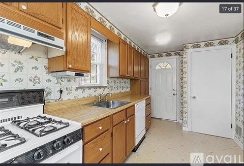 A kitchen with a stove, sink, and cabinets.