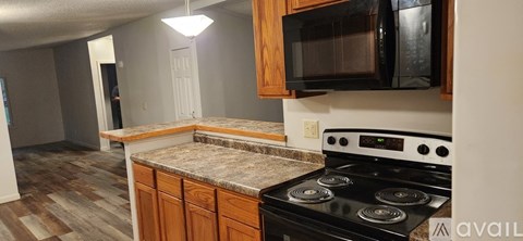 A kitchen with a black stove top oven and wooden cabinets.