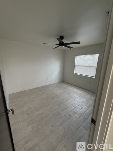 A room with a ceiling fan and a window with blinds.