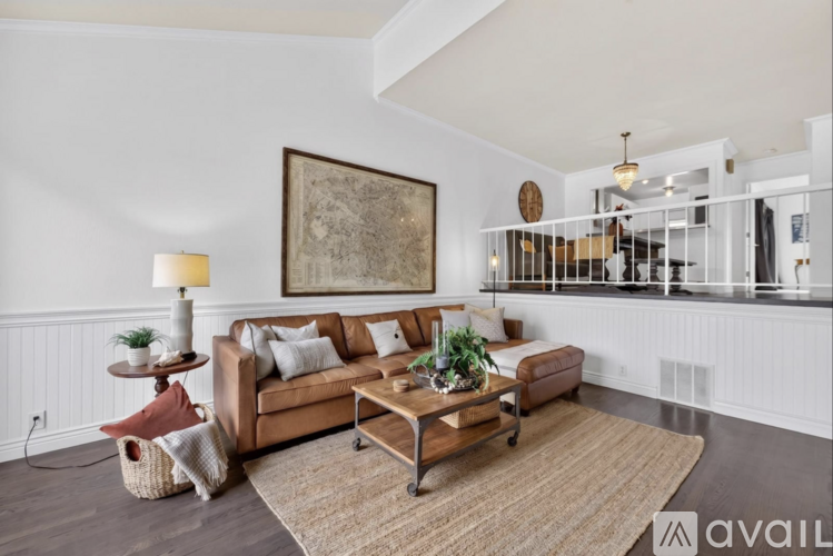A living room with a brown sofa, a wooden coffee table, and a large painting on the wall.