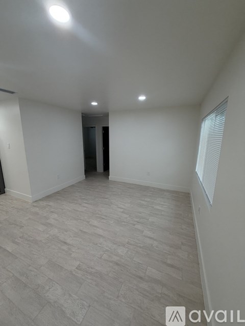 A spacious room with light grey carpeting and a door in the background.