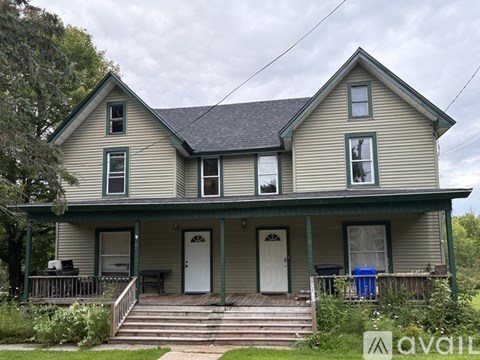 A two-story house with a front porch and a trash can on the steps.