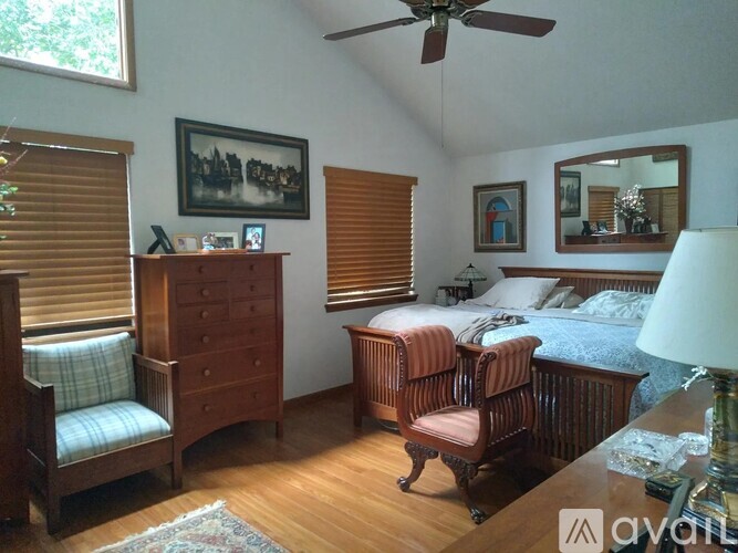 A bedroom with a bed, chair, and dresser.