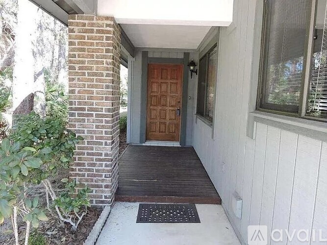 A house entrance with a brown door and a brick pillar.