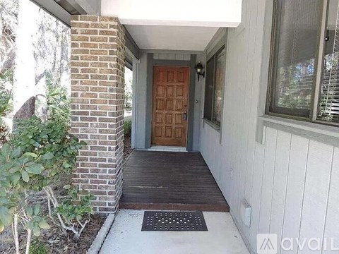 A house entrance with a brown door and a brick pillar.