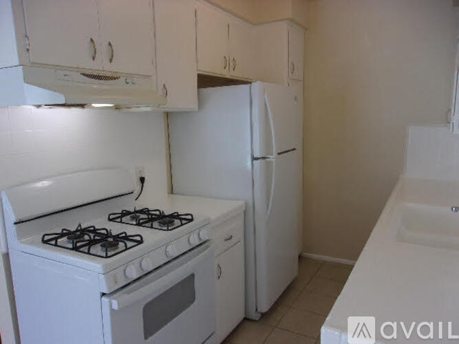 A white kitchen with a stove, refrigerator, and cabinets.