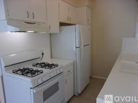 A white kitchen with a stove, refrigerator, and cabinets.