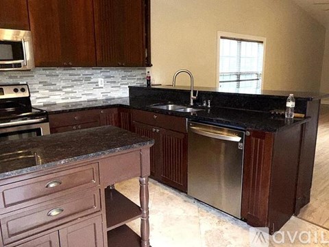 A kitchen with dark wood cabinets and a granite countertop.