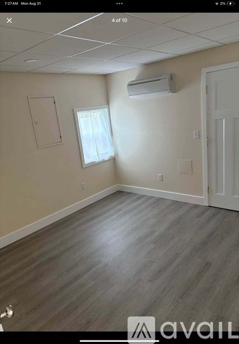 A room with wooden flooring and a window with blinds.