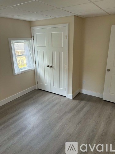 A room with a white door and a window with white curtains.