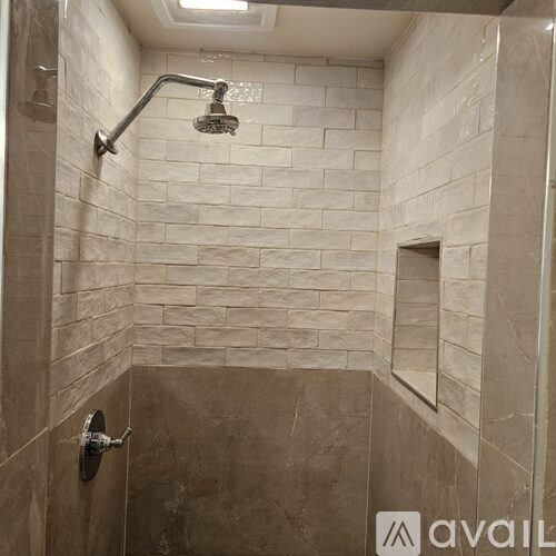 A shower area with a wall of tiles and a shower head.