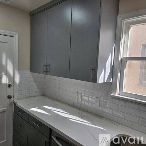 A kitchen with grey cabinets and white subway tiles.