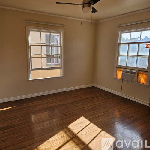 A room with wooden floors and two windows.