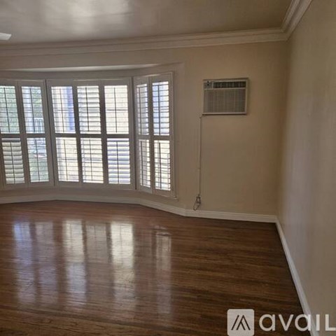 A room with wooden floors and a window with blinds.