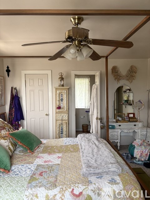 A bedroom with a bed, dresser, mirror, and a ceiling fan.