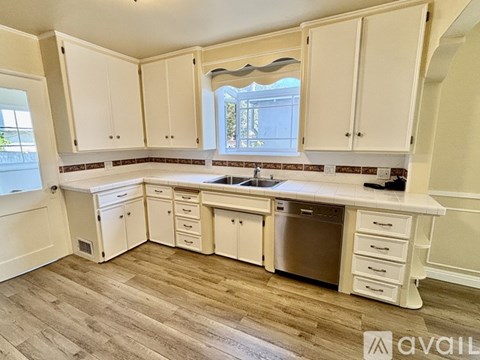 A kitchen with white cabinets and a wooden floor.