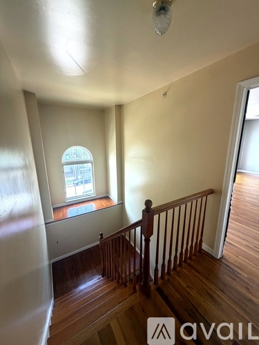 A room with wooden floors and a window with a view of a street.