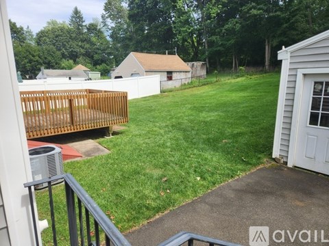 A backyard with a fence, a shed, and a house in the background.