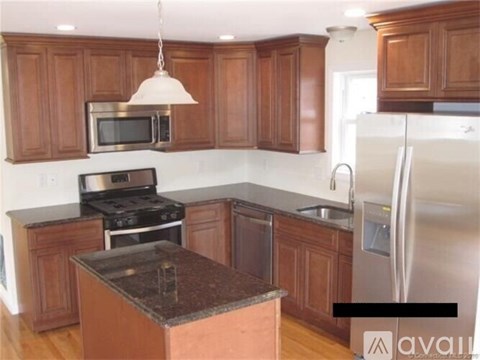 A kitchen with wooden cabinets and a black granite counter.