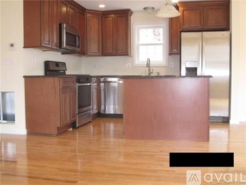 A kitchen with wooden cabinets and a black microwave above the stove.