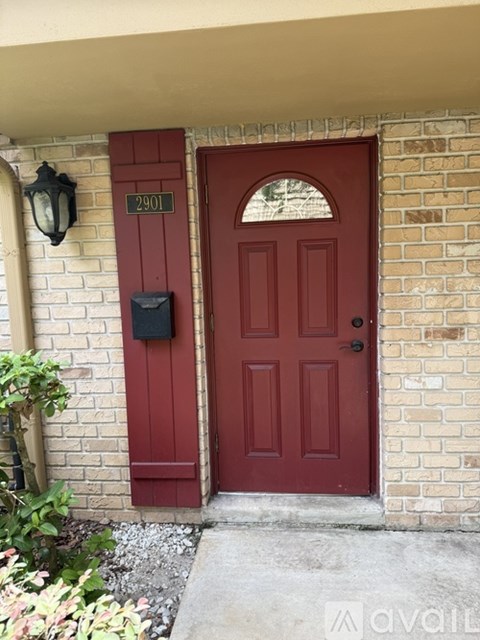 A red door with a mailbox on the side of a brick building.