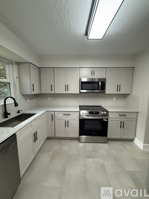 A kitchen with white cabinets and a stainless steel oven.