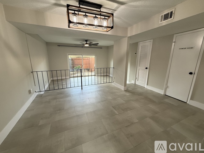 A spacious room with a fan and a window with a view of a building outside.