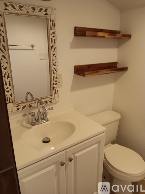 A bathroom with a sink, toilet and mirror.
