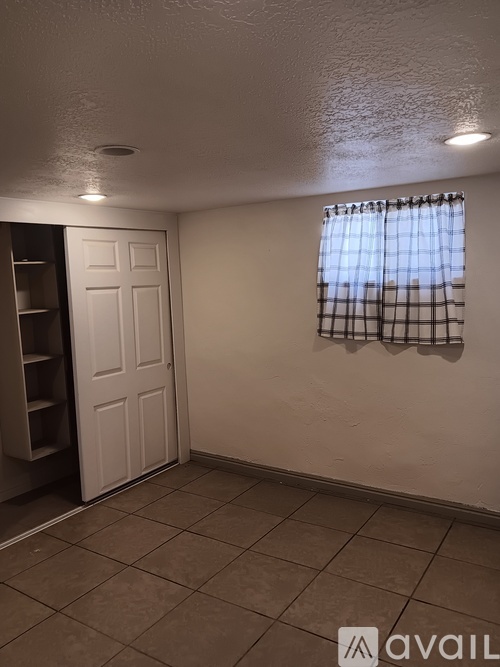 A room with a door and a window with a checkered curtain.