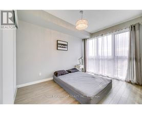 A bedroom with a bed, a chandelier, and a window with curtains.