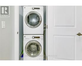 A white washing machine is stacked on top of another white washing machine in a small space.