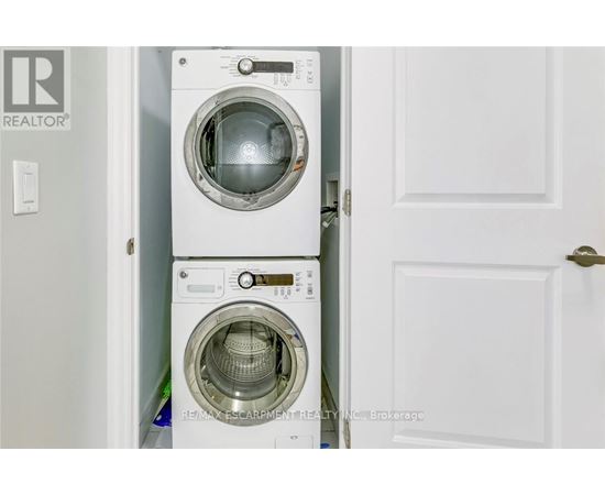 A white washing machine is stacked on top of another white washing machine in a small space.