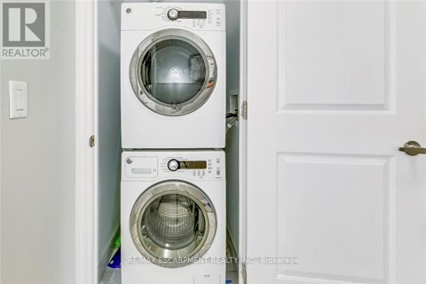 A white washing machine is stacked on top of another white washing machine in a small space.