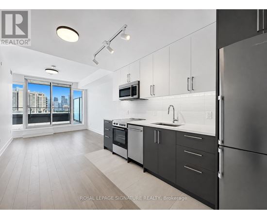 A modern kitchen with a refrigerator, oven, and microwave.