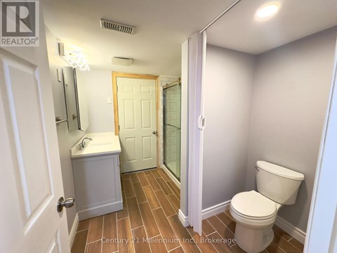 A bathroom with a toilet, sink, and mirror.