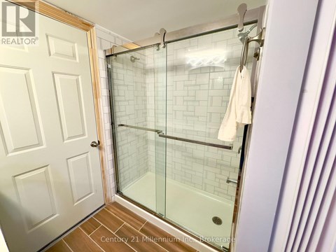 A white door is open to a bathroom with a glass shower stall.