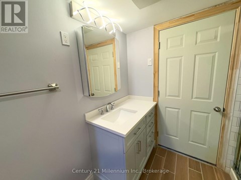A bathroom with a sink, mirror, and a door.
