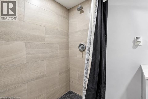 A bathroom with a shower and a black curtain.