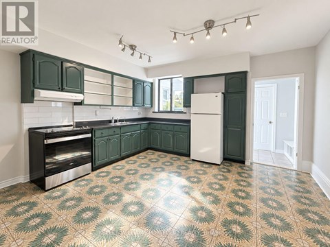 A kitchen with green cabinets and a patterned floor.