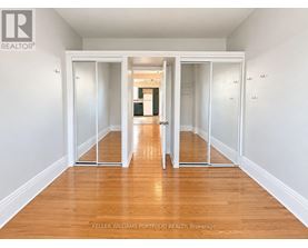 A room with a wooden floor and white walls, with a sliding door in the middle.