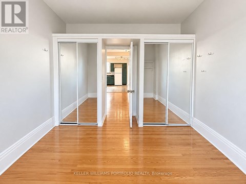 A room with a wooden floor and white walls, with a sliding door in the middle.