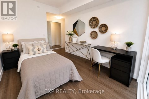 A bedroom with a large bed, a desk with a chair, and a mirror on the wall.