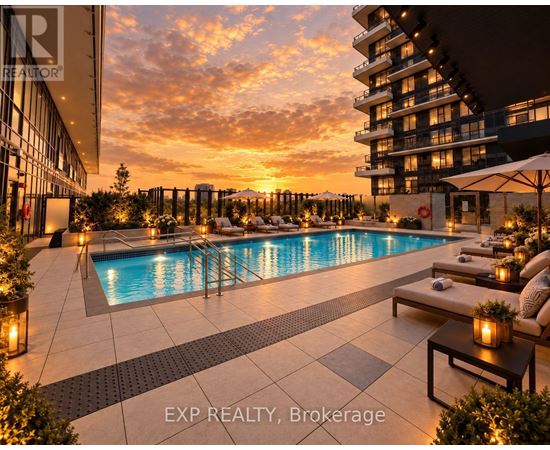A pool area with a sunset in the background and a building on the right.