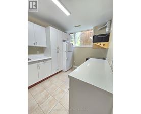 A white kitchen with a refrigerator, cabinets, and a counter.